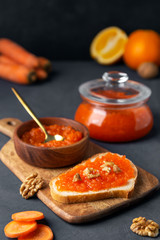 Carrot jam with bread and a jar on a dark background