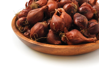 High angle view of natural organic fresh raw red shallot onion on round wooden plate isolated on white background.Taiwan's red onion is water droplets type,skin is red. Food and vegetable concept.