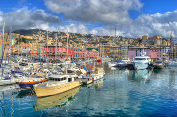 Fototapeta na wymiar Genoa, Italy - Nov 3th 2013: Boats in Genoa harbor, with HDR effect applied. Clouds and hills in the background.