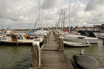 Fototapeta premium Boats on the pier, Marken, Netherlands. Beautiful pier of the island of Marken and typical wooden green houses near the waterfront in the fishing village.