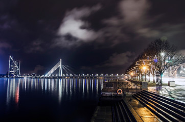 Fototapeta na wymiar View of the cable-stayed bridge and river promenade with Christmas decoration in Riga at night, Latvia