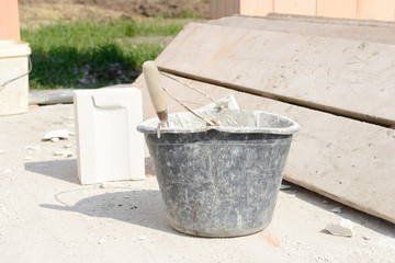 mason bucket, wooden scaffold boards and building stones on construction site