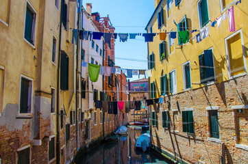 Fototapeta na wymiar Laundry hanging out of a typical Venetian facade, Italy. Narrow canal street with colorful buildings and boats in Venice and clothes dry on a rope, Venice, Italy.