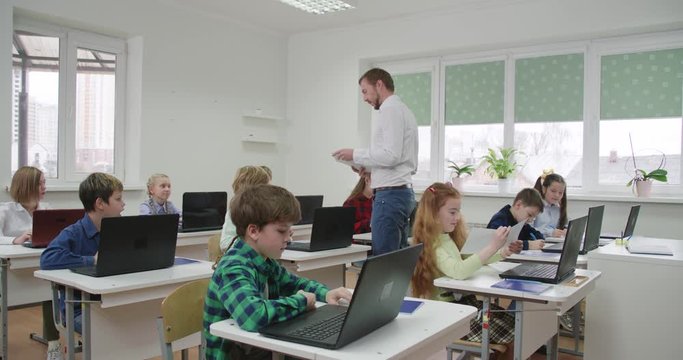 Education at modern school, the teacher gives students tests on sheets of paper.