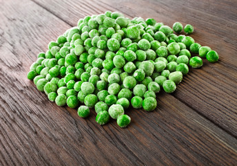 Heap of frozen pea on a old wooden table.
