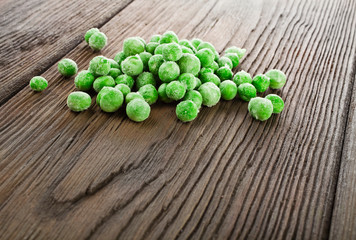 Heap of frozen pea on a old wooden table.