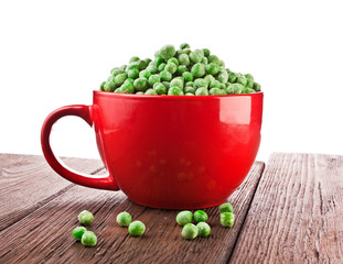 A red cup with frozen pea on a old wooden table.