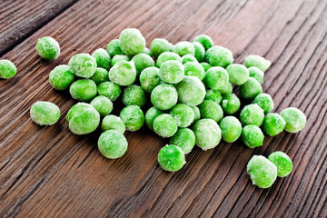 Heap of frozen pea on a old wooden table.