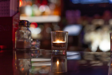 solitary candle slowly burning at a bar