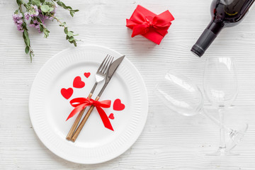 Romantic dinner on Valentines Day. Wine, plate, present box on white background top-down