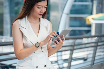 Asian woman holding credit cart and using tablet to shopping online.Shopaholic girl selecting products to cart in online website And pay via internet banking.