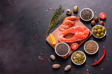 Raw trout red fish steak served with herbs and lemon and olive oil on a dark background