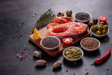 Raw trout red fish steak served with herbs and lemon and olive oil on a dark background