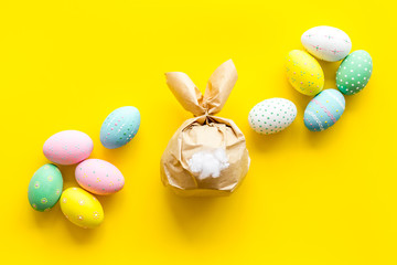 Easter symbols. Bunny and painted eggs on yellow background top-down
