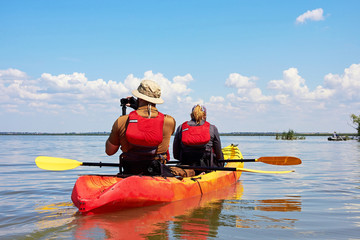 Man and woman on kayak taking a photo with action camera