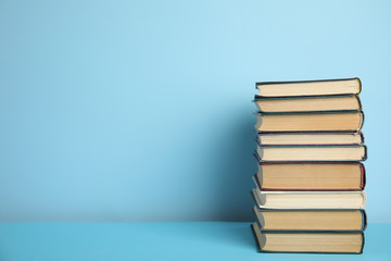 Stack of hardcover books on light blue background, space for text