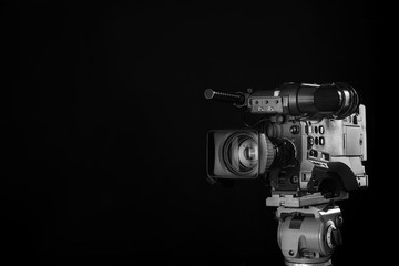 Modern professional video camera on black background. Space for text