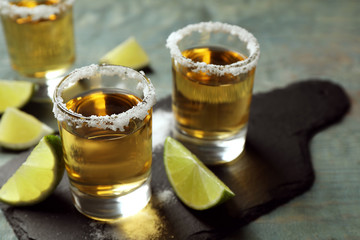 Mexican Tequila shots, lime slices and salt on blue wooden table