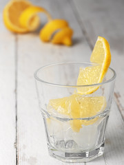 Glass with ice cubes and sliced lemon on white wooden background.Close up, shallow depth of field.