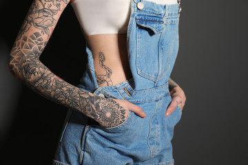 Woman with tattoos on body against black background, closeup