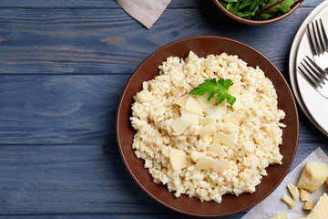 Delicious risotto with cheese on blue wooden table, flat lay