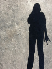 Blurry shadaw and silhouette of a women stand on the road.Light and shadow women.The sun is casting over the wall.pointing finger.Hand symbol.black and white background