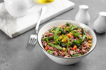 Tasty brown rice with vegetables on grey table