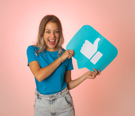 Happy young woman holding Like symbol in internet networking and social media notification icons