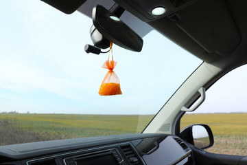 Air freshener hanging on rear view mirror in car