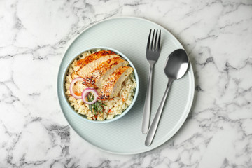 Delicious chicken risotto served on white marble table, top view