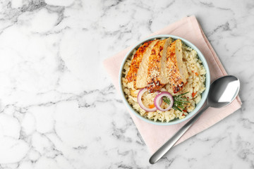 Delicious chicken risotto served on white marble table, flat lay. Space for text