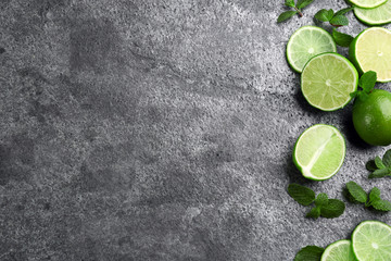 Lemonade layout with juicy lime slices and mint on grey table, top view. Space for text