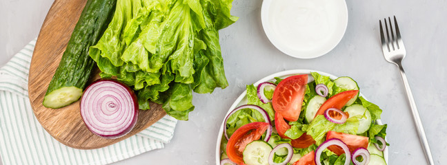 Healthy vegetarian dish on table, vegetable salad with fresh tomato, cucumber, lettuce, red onion on gray concrete background. Diet menu. Top view. Flat lay, mockup, template