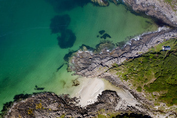 Fototapeta na wymiar Drone footage of waves lapping up onto rocks in Portuairk Bay, Scotland