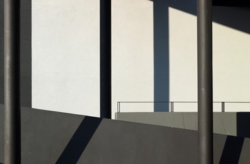  Interior of a building with black columns, gray concrete parapets and shadows on the white wall background. Background for copy space