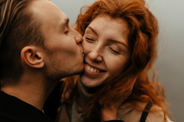 Couple in love portrait. Portrait of happy young woman smiling when her boyfriend kissing her
