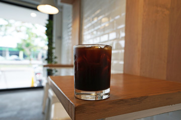 Close up glass of iced black coffee on wooden table