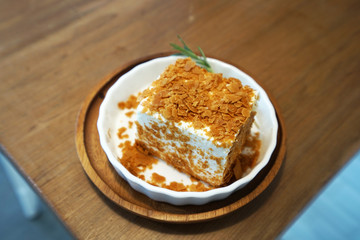 Close up piece of cheesecake topped with cornflakes on wooden tray table