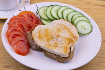 Heart shaped vegetables and steak on wooden background. Breakfast for a loved one.