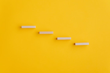 Four blank wooden pegs placed in a stairway like structure