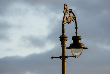 Fototapeta na wymiar An old fashioned vintage street oil lamp sits against a blue sky, Bath, England