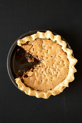 Homemade Chocolate Walnut Derby Pie on a black surface, top view. From above, overhead, flat lay.