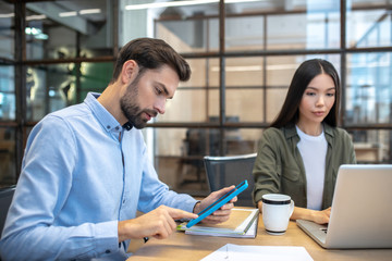 Two employees working in the office and looking busy