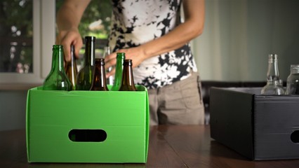Recycling Glass. A woman sorts colored glass bottles from the clear glass at home