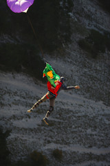 Base jumper in free fall closeup, at the time of opening the parachute, against the background of the dark rocky slope, top view.