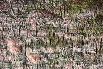 Natural cave in sandstone rock, former bank of Gauja river. Carved wall in Gutmanis cave in...