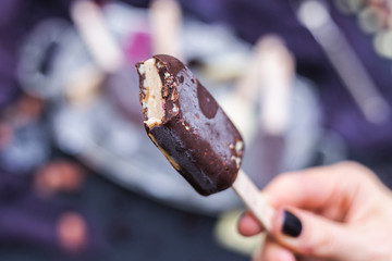 Female hand holding a raw vegan ice cream made of raw food ingredients with blurred background. Ice cream bite.