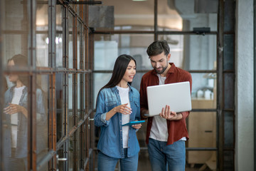 Bearded handsome man in a brown shirt discussing work issues with colleague