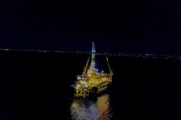 Towing of the oil platform. Oil platform at night in the light of its own lighting. Drilling platform in the port.