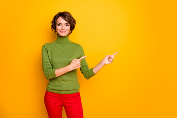Sale. Photo of attractive funny lady indicate fingers empty space advising black friday low prices wear casual green turtleneck red pants isolated yellow color background